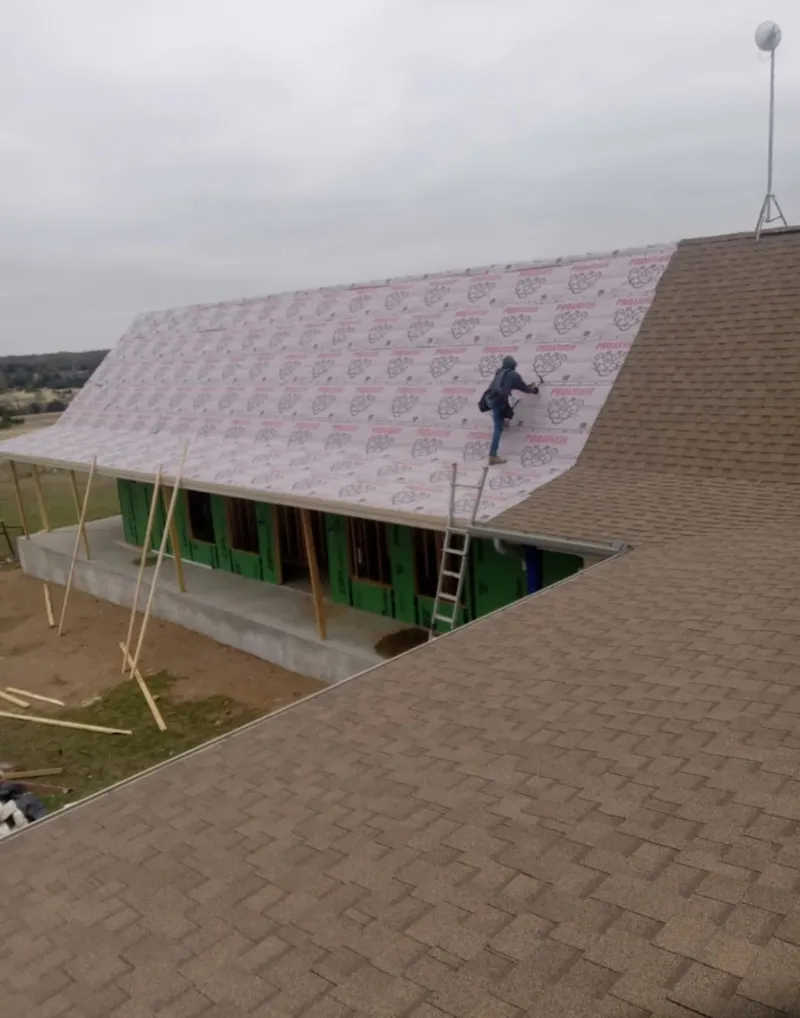 Worker preparing underlayment for a metal roof installation in Beech Grove